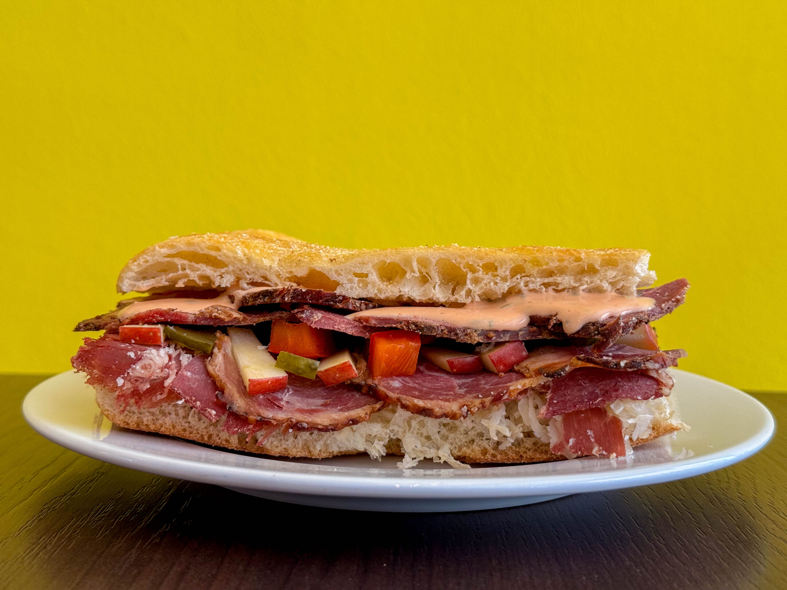 Pastrami Focaccia vor gelber Wand bei Luzi & Hank